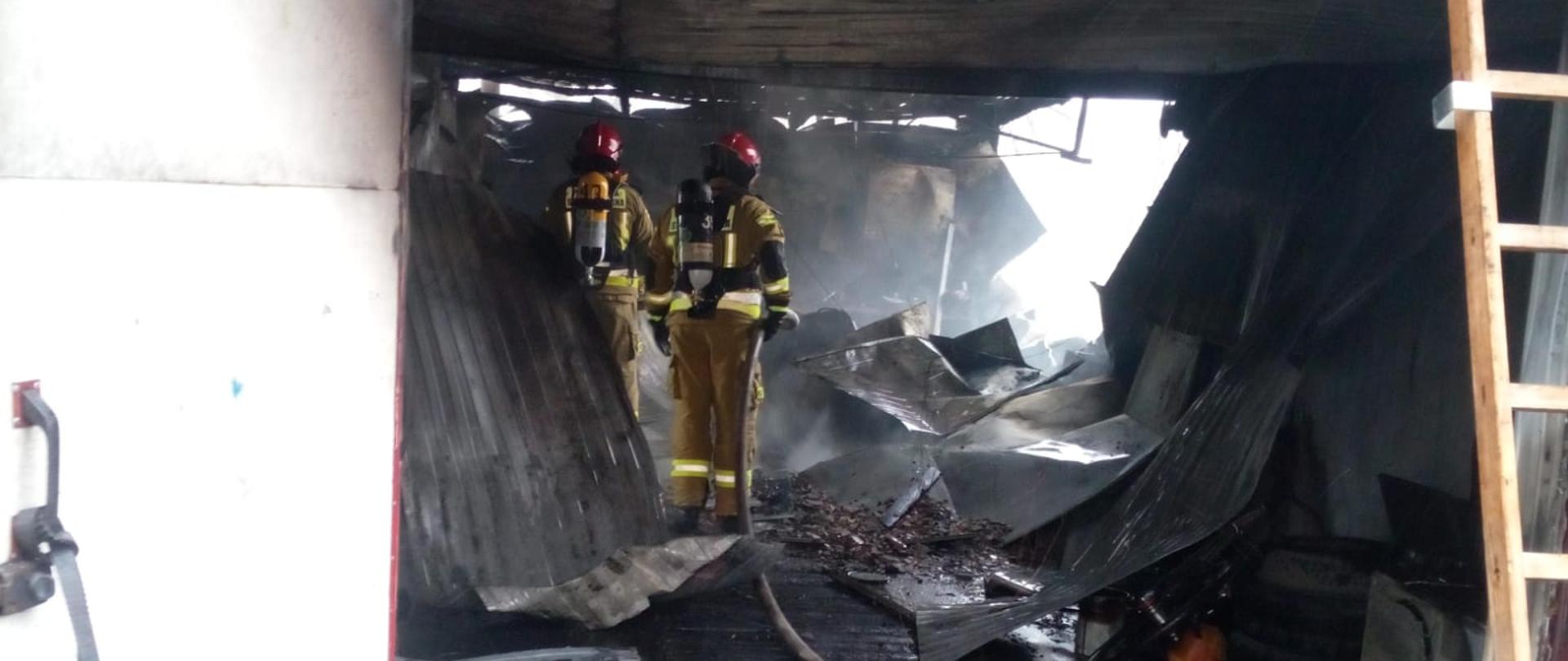 Strażacy w aparatach oddechowych sprawdzają spalony garaż