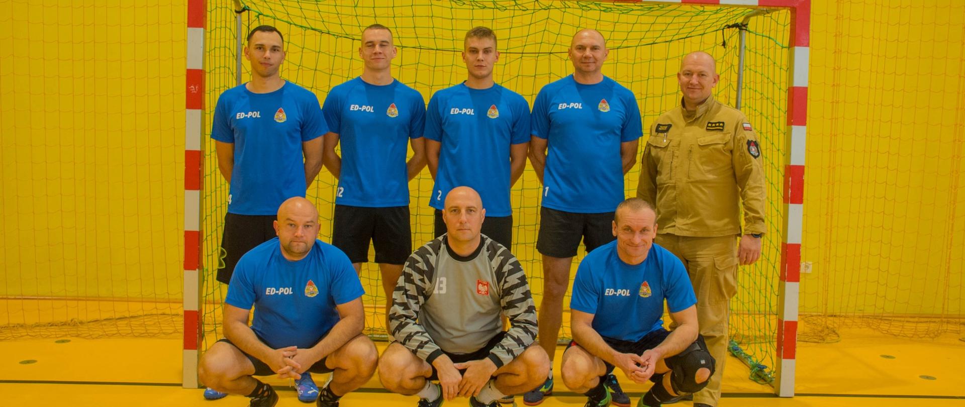 Zdjęcie przedstawia drużynę strażaków z Z-cą Komendanta Powiatowego na tle bramki. Fotografia wykonana w strojach sportowych po zakończeniu turnieju charytatywnego.