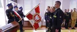 Nowo przyjęci strażacy składają rotę ślubowania naprzeciw pocztu sztandarowego.