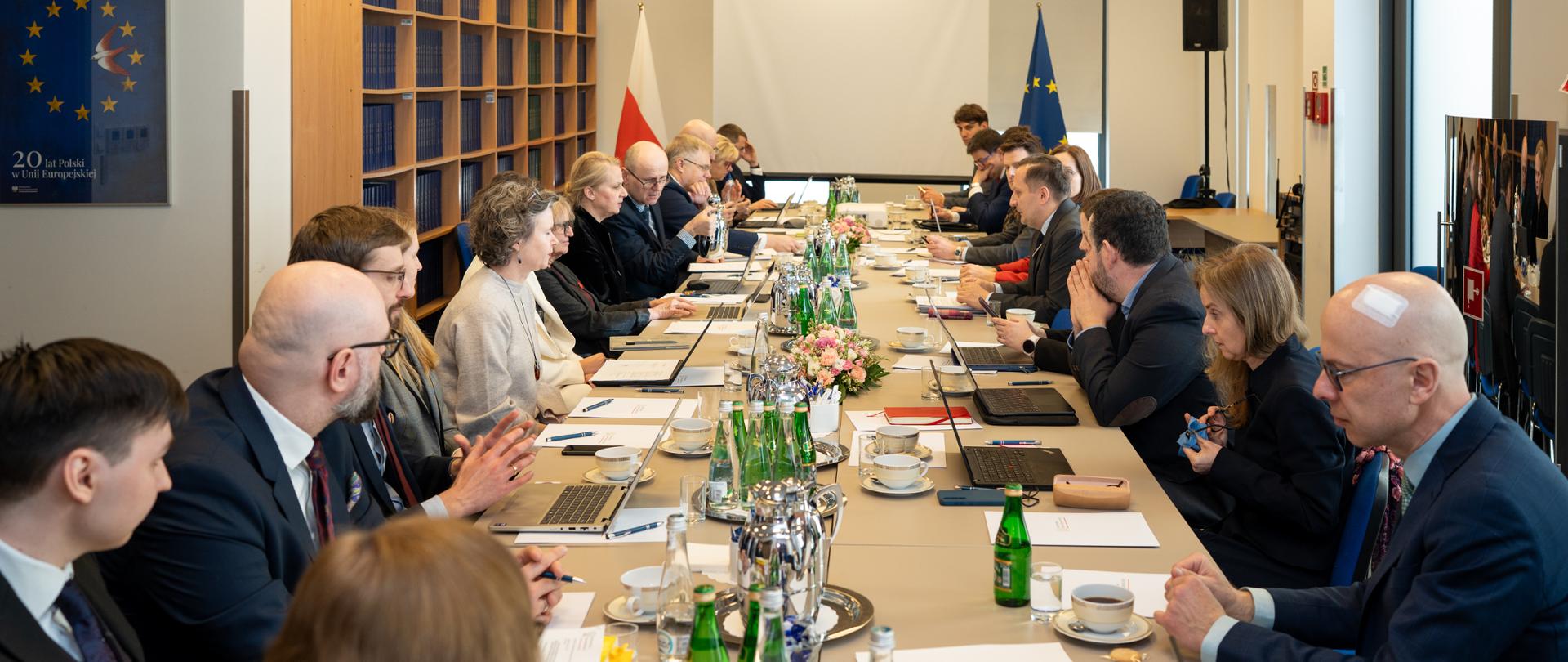 Grono osób siedzi przy stole.