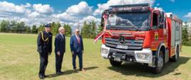 Wojewoda pomorski, pomorski komendant wojewódzki Państwowej Straży Pożarnej oraz wójt gminy Parchowo oglądają nowy samochód gaśniczy.