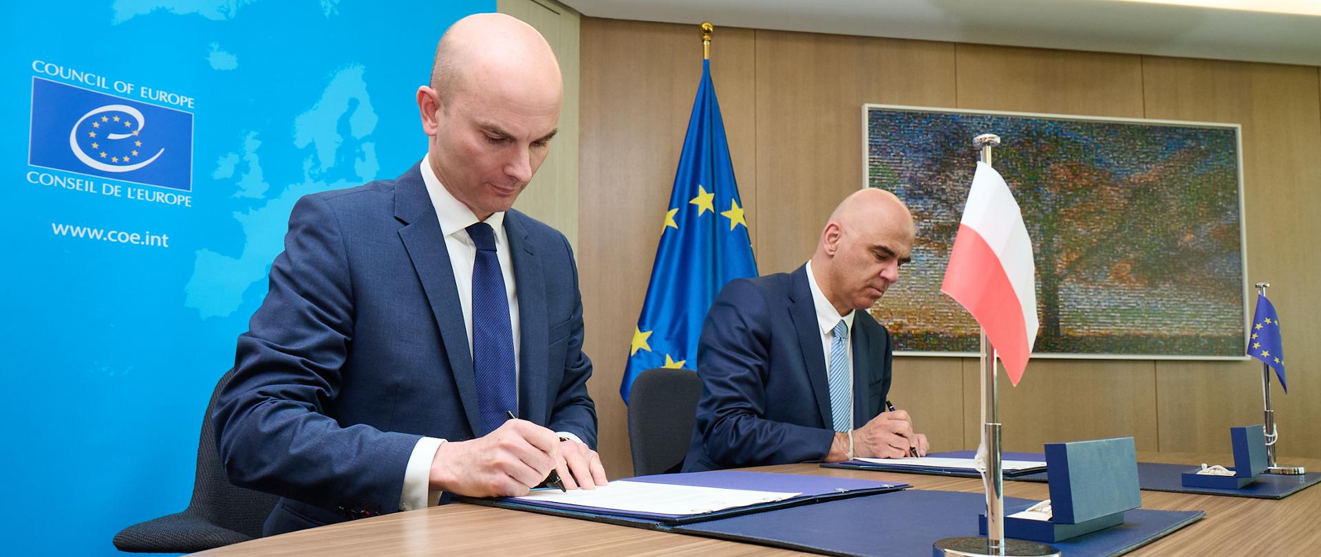 Podpis składają zastępca Stałego Przedstawiciela Rzeczypospolitej Polskiej przy Radzie Europy w Strasburgu, Hubert Czerniuk oraz Sekretarz Generalny Rady Europy, Alain Berset.