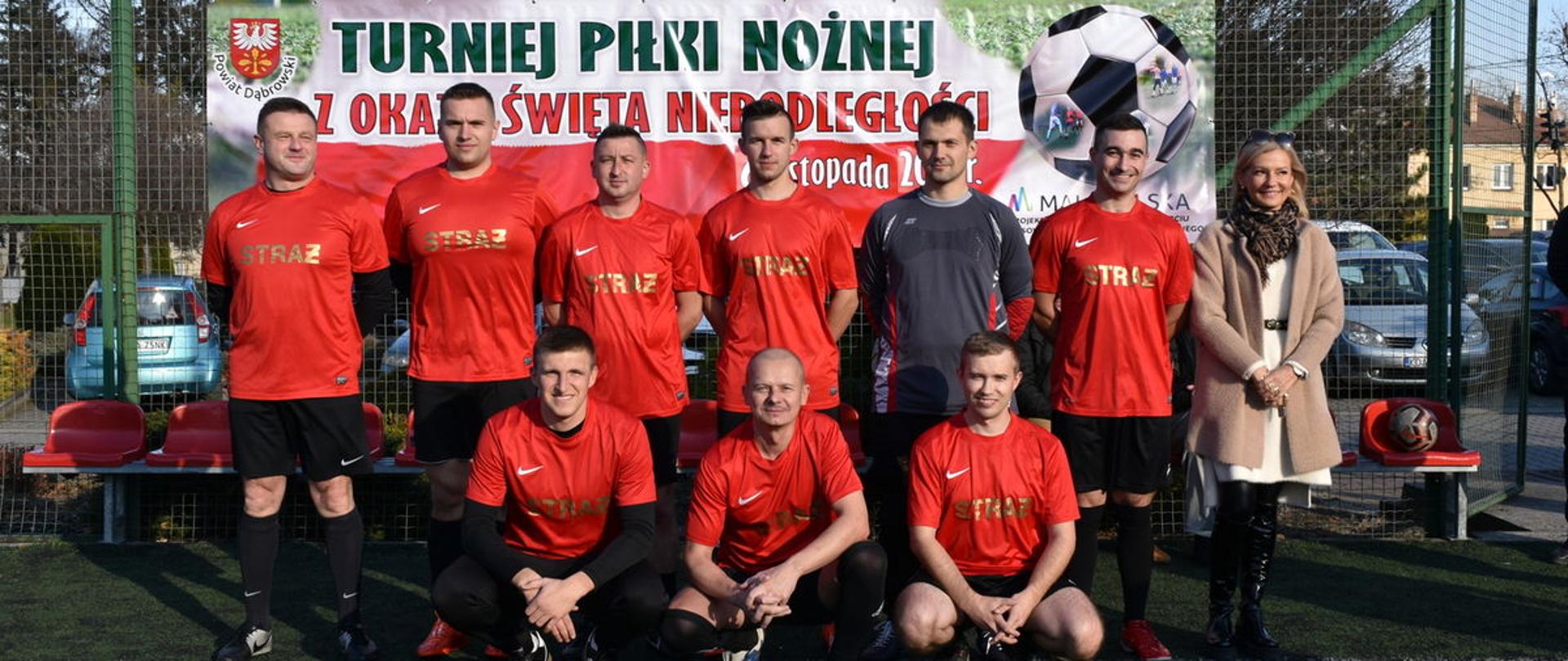 Na zdjęciu drużyna strażaków na tle baneru