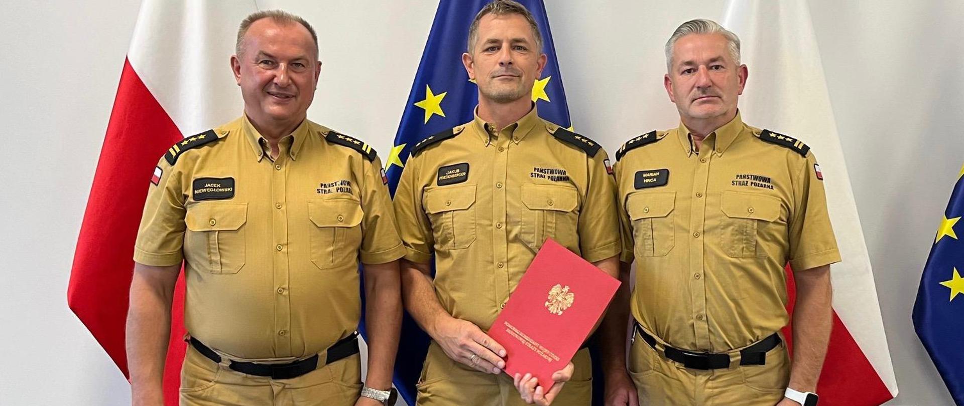 Pomorski Komendant Wojewódzki PSP starszy brygadier Jacek Niewęgłowski wraz ze swoim zastępcą starszym brygadierem Marianem Hincą oraz rzecznikiem w Komendzie Wojewódzkiej PSP w Gdańsku kapitanem Jakubem Friedenberger stoją na tle flag Polskiej i Unijnej.