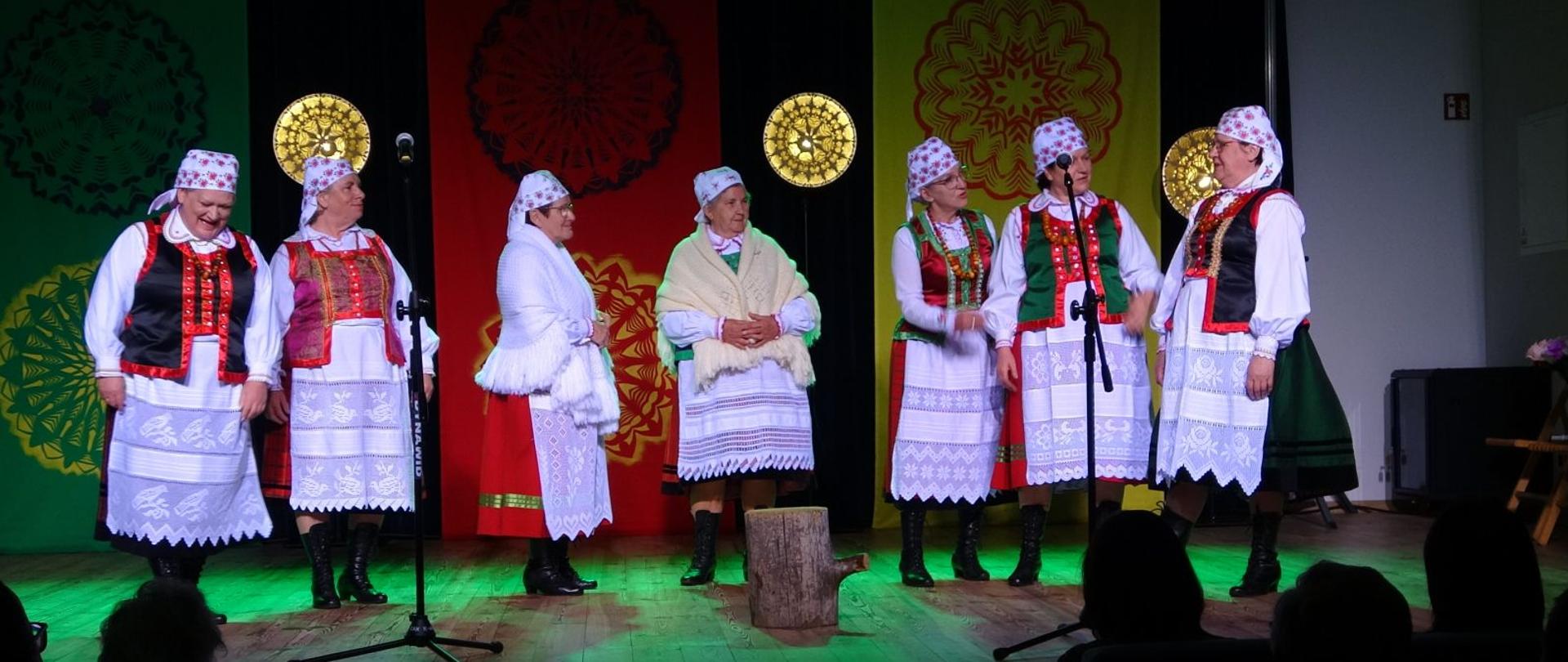 grupa kobiet w kurpiowskich strojach występuje na scenie