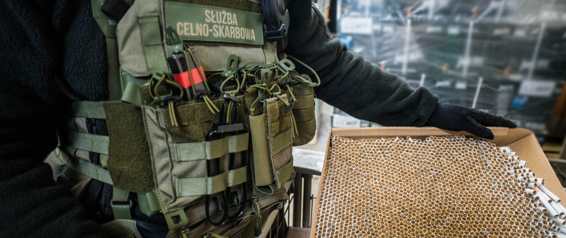 Funkcjonariusz KAS trzyma karton z nielegalnymi papierosami