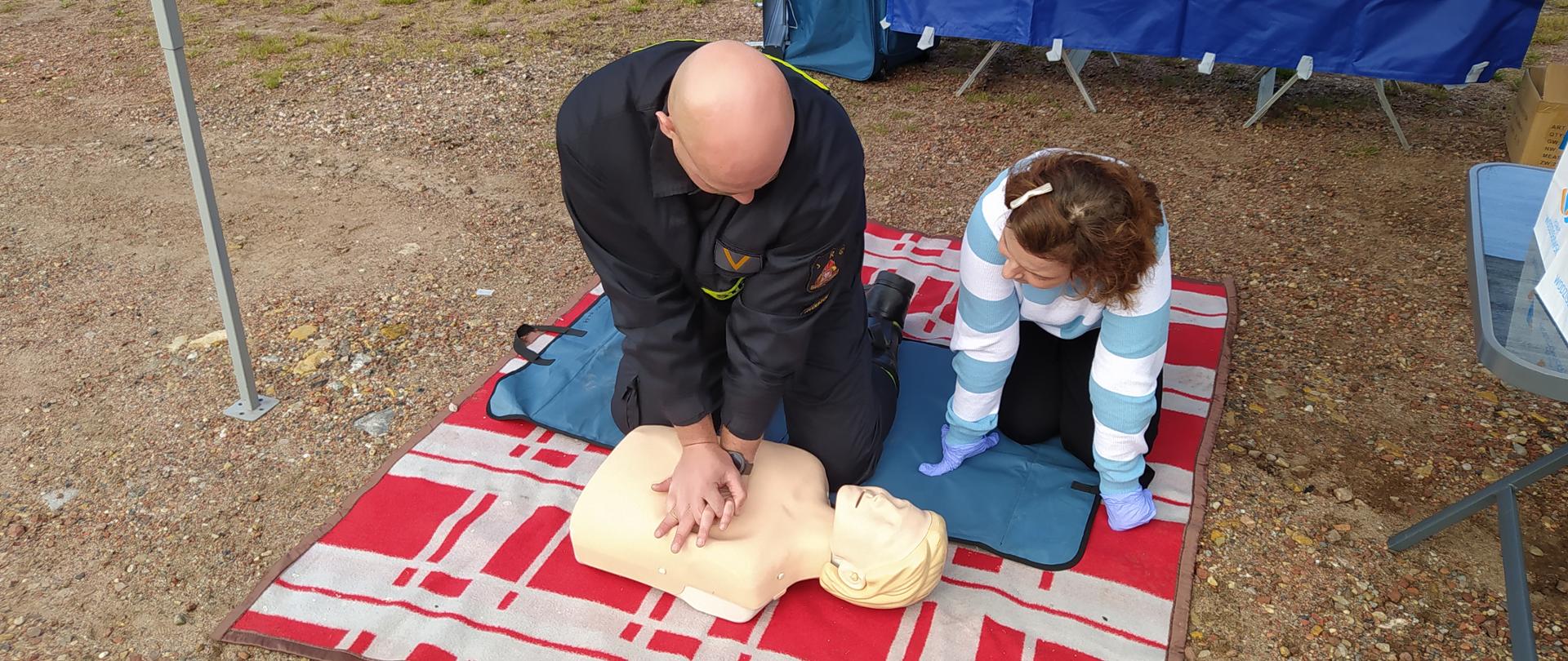 Na zdjęciu strażak uczy pierwszej pomocy kobietę