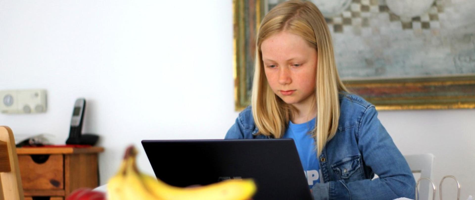Dziewczynka pisząca w domu na komputerze