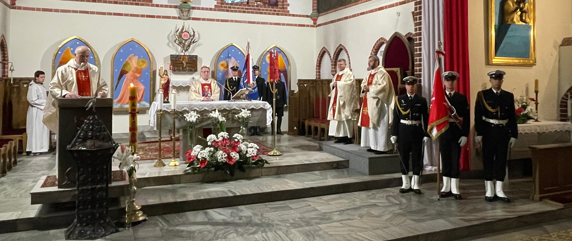 Prezbiterium. Po lewej ksiądz przy ambonie po prawej poczet sztandarowy marynarki wojennej w tyle inni księża i poczet sztandarowy komendy straży w Sopocie 