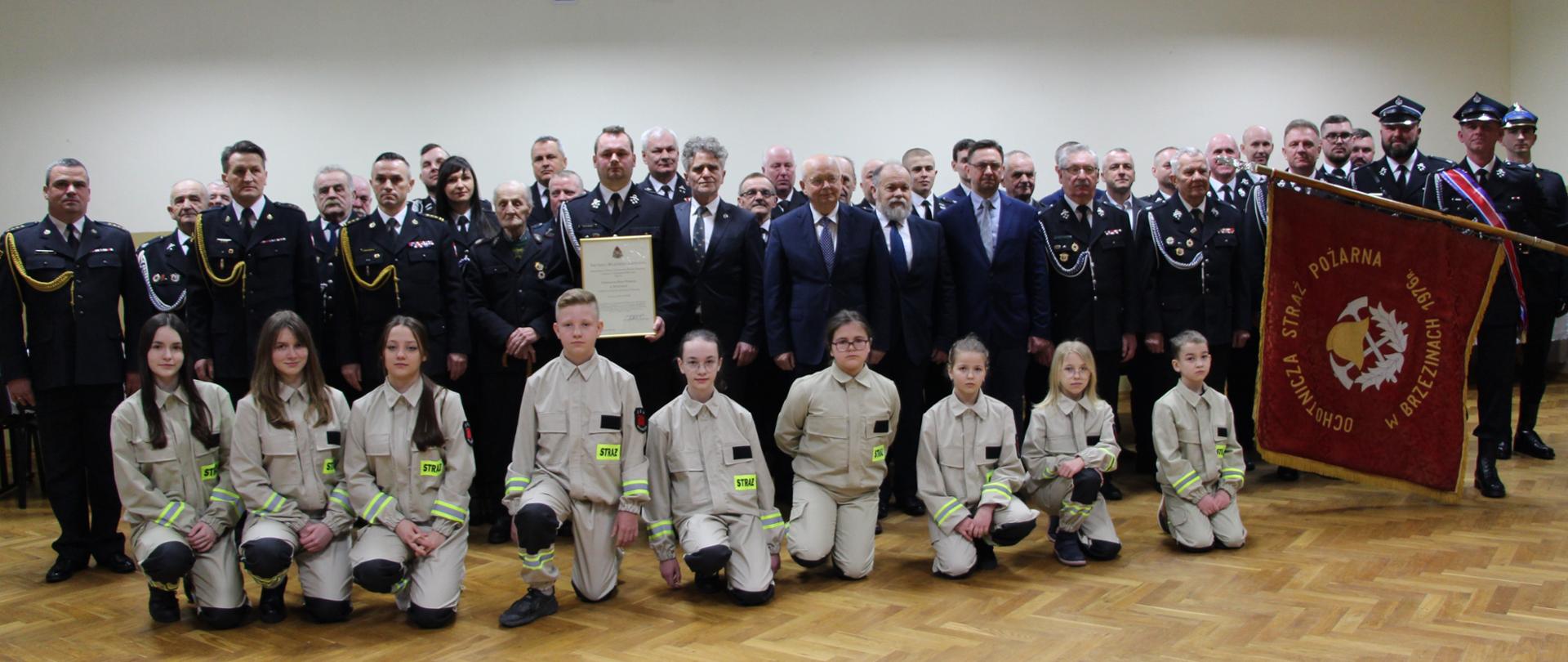 Na zdjęciu druhowie Ochotniczej Straży Pożarnej z Brzezin wraz z zaproszonymi na uroczystość gośćmi. Z lewej strony sztandar OSP Brzeziny a w pierwszym szeregu lokalna Młodzieżowa Drużyna Pożarnicza.