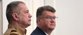 Wiceminister MSWiA Maciej Wąsik oraz zastępca komendanta głównego PSP nadbrygadier Arkadiusz Przybyła siedzący na krzesłach w sali konferencyjnej KPRM