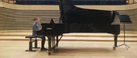 Uczennica gra na fortepianie na scenie sali koncertowej PSM