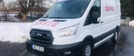 Zdjęcie przedstawia samochód kwatermistrzowski SLKw Ford Transit na tle placu wewnętrznego Komendy Powiatowej Państwowej Straży Pożarnej w Wodzisławiu Śląskim