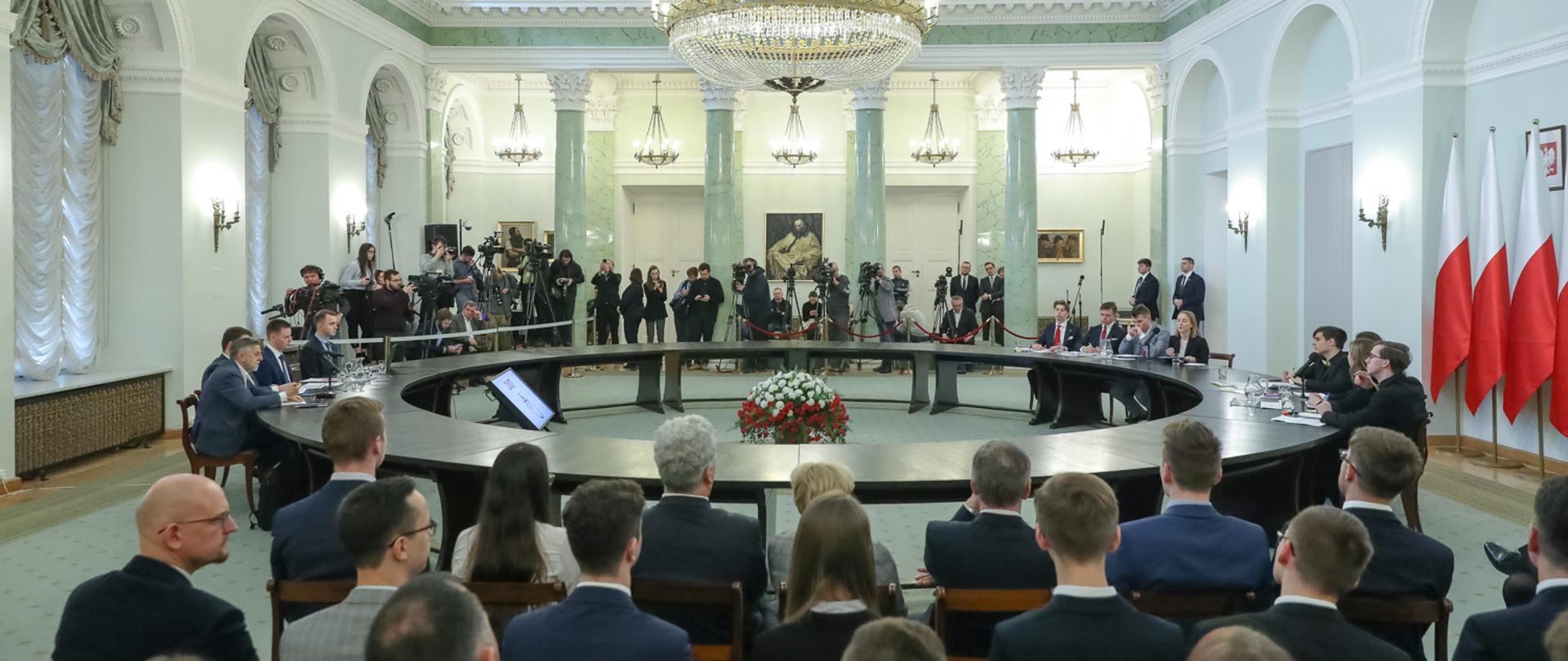 na zdjęciu uczestnicy debaty siedzą przy okrągłym stole