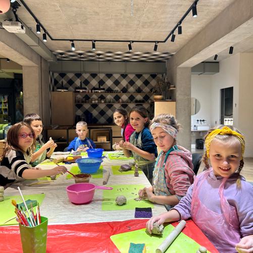 Grupa dzieci przy stole przygotowuje wyroby z gliny