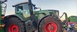 Ciągnik rolniczy stojący na drodze. Dookoła widać uszkodzone elementy samochodu osobowego.