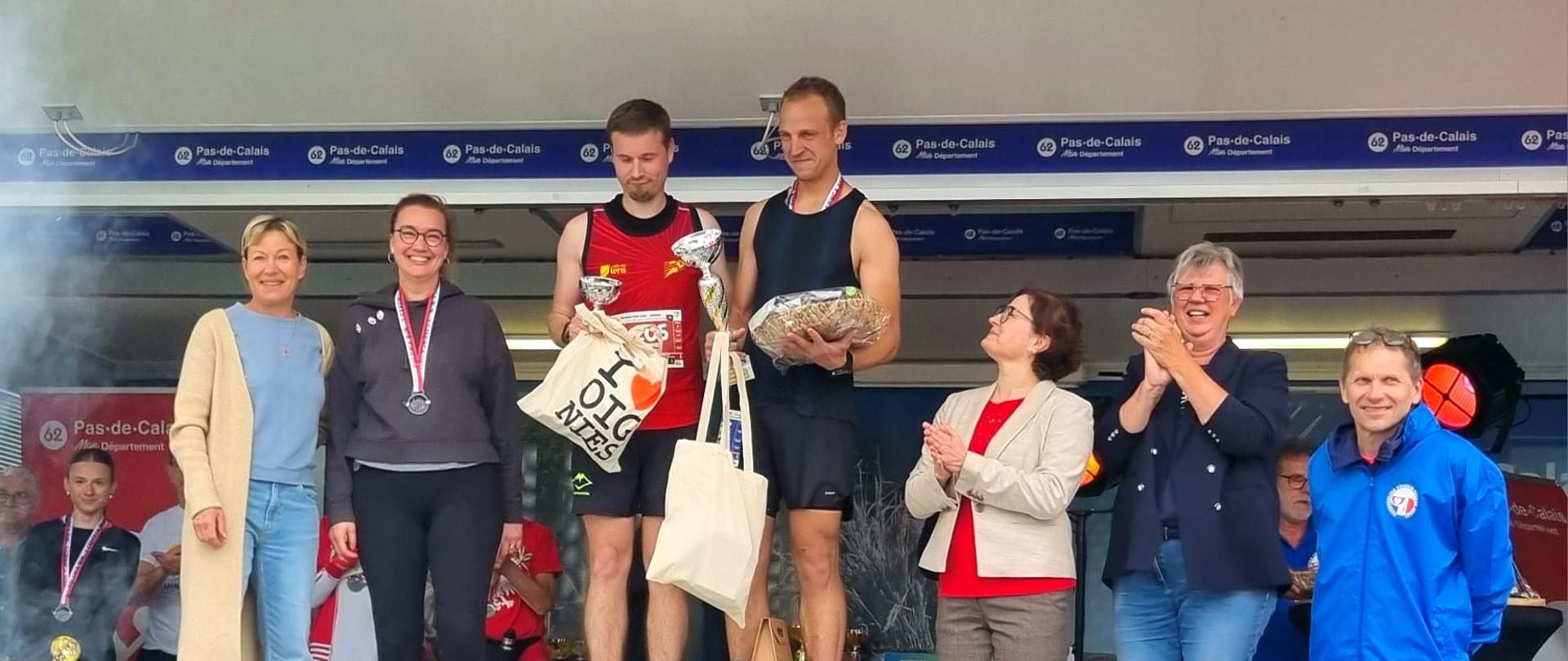Zdjęcie przedstawia osoby, które stoją na podium.