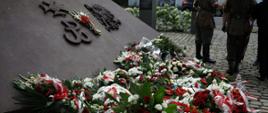 pomnik na której znajduje się znak Polski walczącej oraz orzej, przed pomnikiem leży duża ilość biało czerwonych wieńcy 