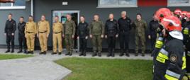 Zdjęcie przedstawia przedstawicieli Państwowej Straży Pożarnej, Wojskowej Straży Pożarnej oraz przedstawicieli Delegatury Wojskowej Ochrony Przeciwpożarowej w Bydgoszczy na tle jednostki wojskowej w Leźnicy Wielkiej.