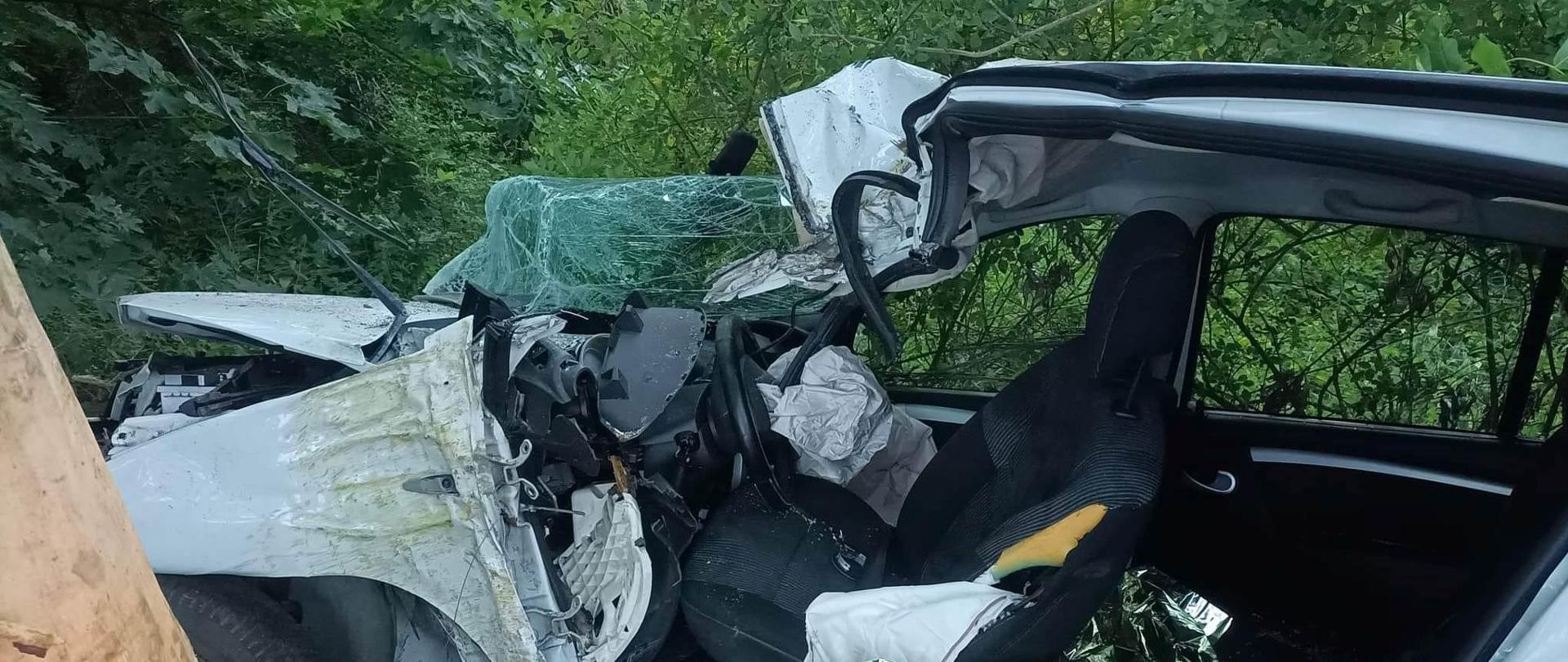 Widać mocno uszkodzony biały samochód