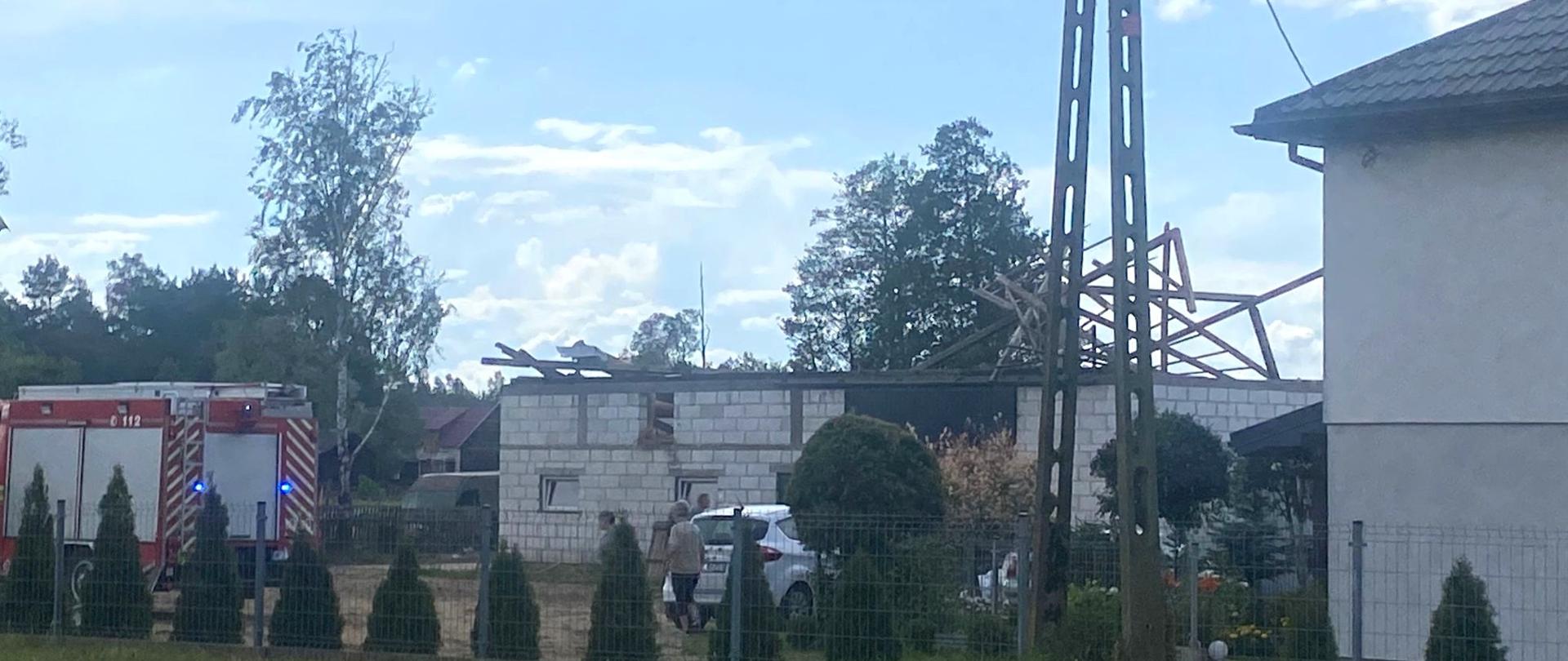 27 czerwca bieżącego roku około godz. 14:45 silny i porywisty wiatr zerwał dach na budynku obory i na nieużytkowanym drewnianym budynku mieszkalnym w miejscowość Krukowo gm. Chorzele.
Po dojeździe jednostek ochrony przeciwpożarowej na miejscu zdarzenia zastano porozrzucane elementy dachu oderwane w całości przez silny wiatr z budynku gospodarczego - obory. Jeden z kawałków blachy trapezowej zawisł na napowietrznej linii energetycznej uszkadzając ją. Inny natomiast znajdował się na dachu pobliskiego kościoła na wysokości około 10 metrów od gruntu. Fragmenty blachy porozrzucane były również po sąsiednich posesjach.
Dwie posesje dalej od miejsca zdarzenia fragment dachu spadł na zaparkowane przed domem samochody osobowe całkowicie niszcząc jeden z nich i uszkadzając drugi. Oderwany dach uszkodził również elewację budynku i częściowo murowane ogrodzenie posesji. Na sąsiedniej posesji wiatr zerwał jedną stronę pokrycia (eternit) nieużytkowanego domu jednorodzinnego konstrukcji drewnianej.
Działania strażaków początkowo polegały na zabezpieczeniu miejsca zdarzenia, uprzątnięciu porozrzucanych elementów dachu z okolicy oraz zabezpieczeniu naderwanej linii energetycznej. Następnie przystąpiono do działań związanych z uszkodzonymi budynkami, tj. rozebrano pozostałości więźby dachowej obory oraz uprzątnięto przewrócone ściany szczytowe, zabezpieczono plandekami dach drewnianego domu oraz zdjęto z dachu kościoła fragment zaczepionej blachy.
Równocześnie ze strażakami swoje działania prowadziło Pogotowie Energetyczne - wymieniali naderwaną linię oraz korzystając z podnośnika hydraulicznego usunęli blachę wiszącą na linii. Zerwaniu uległ także światłowód internetowy który zamocowany był na słupach PGE i leżał on w poprzek drogi powiatowej. Ruch kołowy na drodze był całkowicie zamknięty.
Opracował: asp. Sekuna Rafał.
Zdjęcia: KP PSP Przasnysz.
