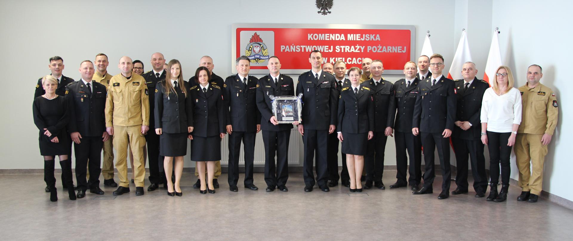 Na zdjęciu przedstawiono zgromadzonych funkcjonariuszy i pracowników Komendy Miejskiej Państwowej Straży Pożarnej w Kielcach wraz z odchodzącym komendantem.
