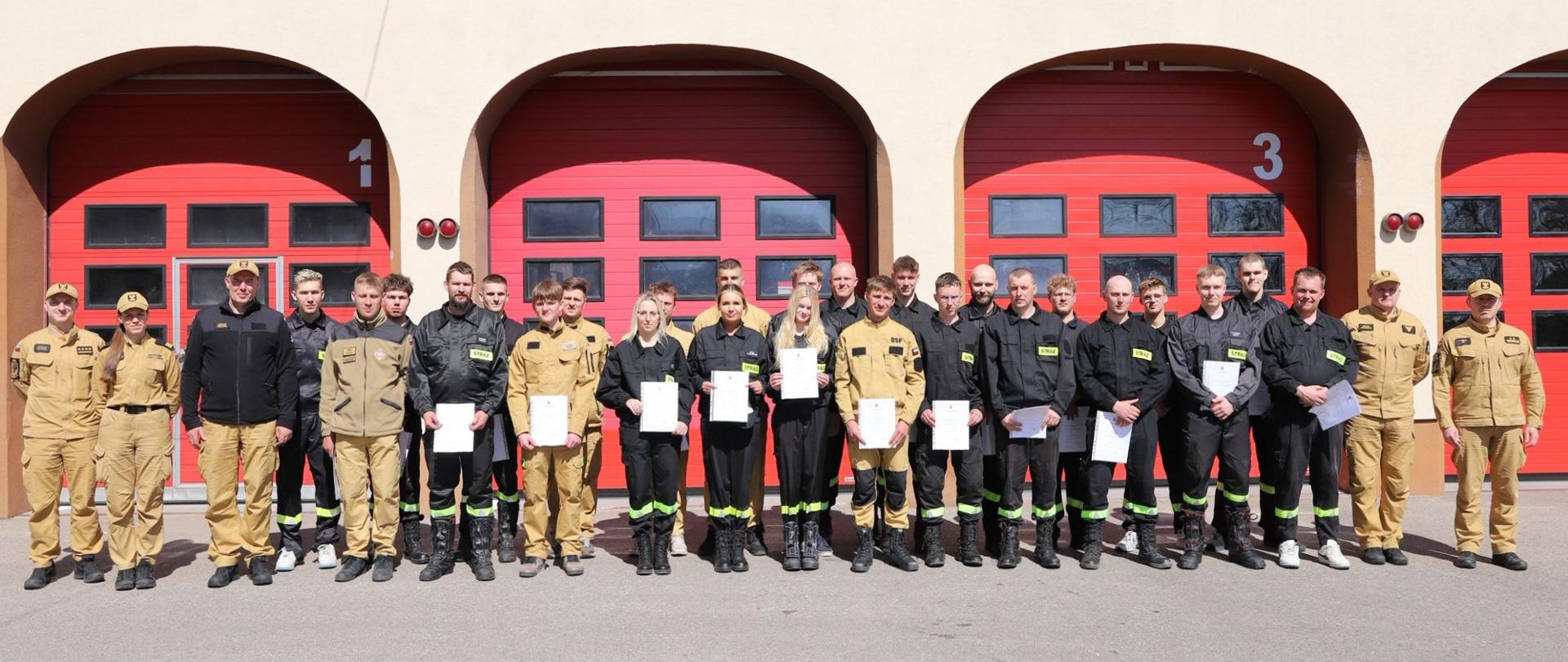 Zdjęcie grupowe po zakończonym szkoleniu podstawowym strażaków OSP na tle budynku Komendy.