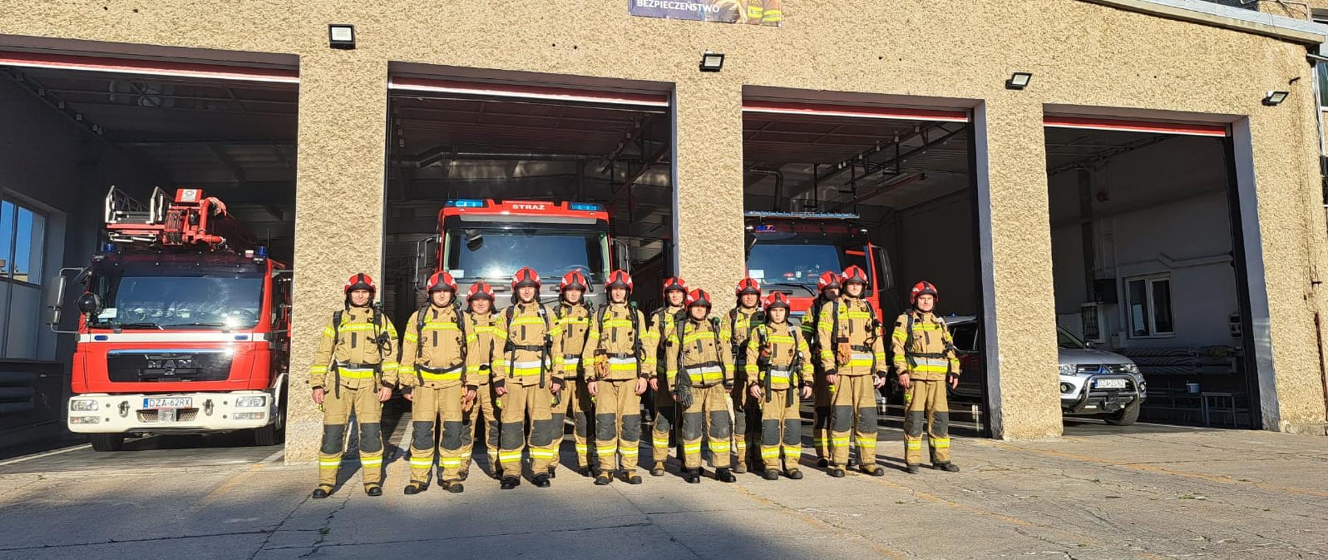 strażacy przed garażem stoją w umundurowaniu bojowym