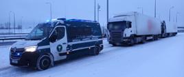 Od lewej: oznakowany furgon podlaskiej Inspekcji Transportu Drogowego z włączonymi niebieskimi światłami i stojący za nim kontrolowany ciągnik siodłowy z podpiętą naczepą. Z tyłu stoi drugi podobny zestaw.