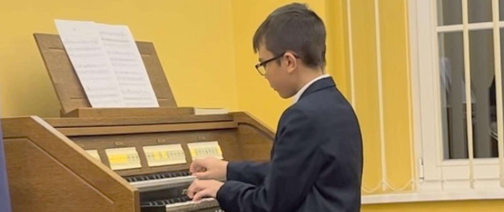 Chłopiec grający na organach elektronicznych.