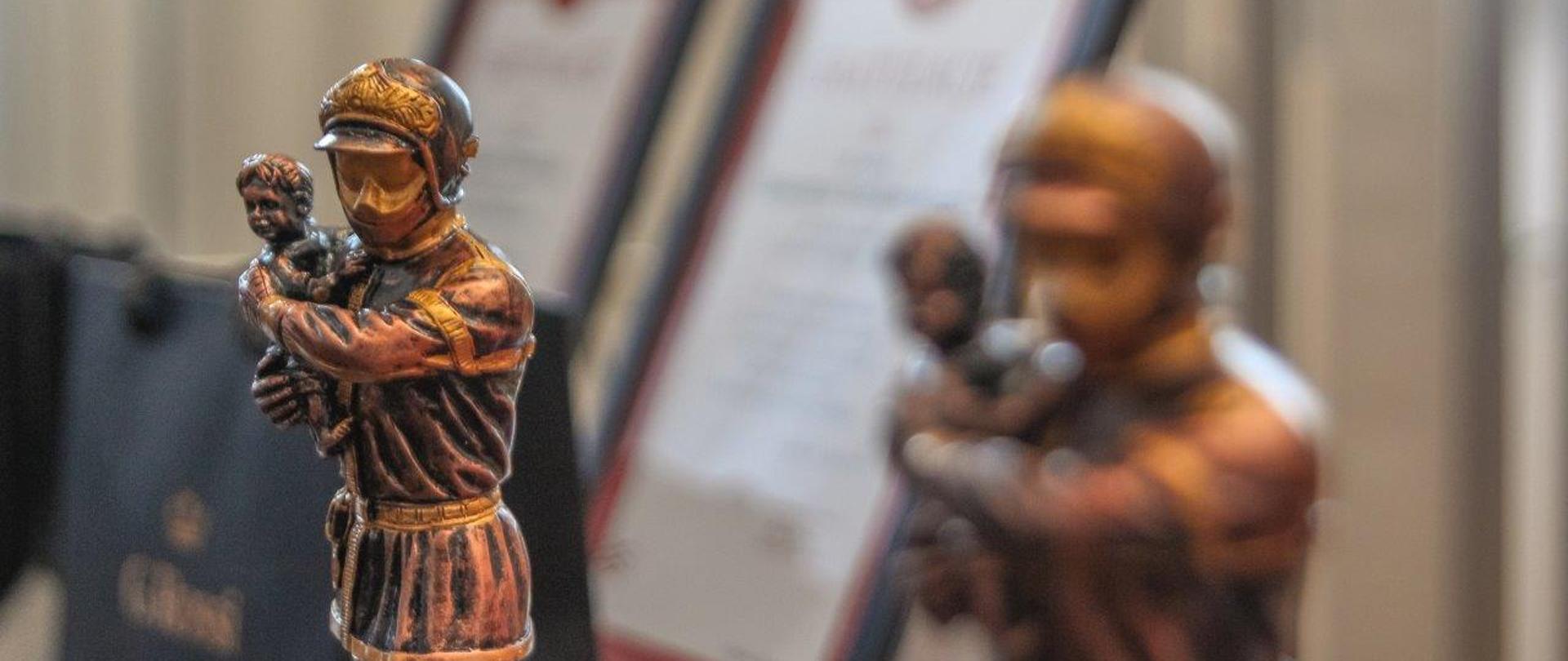 Na pierwszym planie figurka z brązu strażaka.