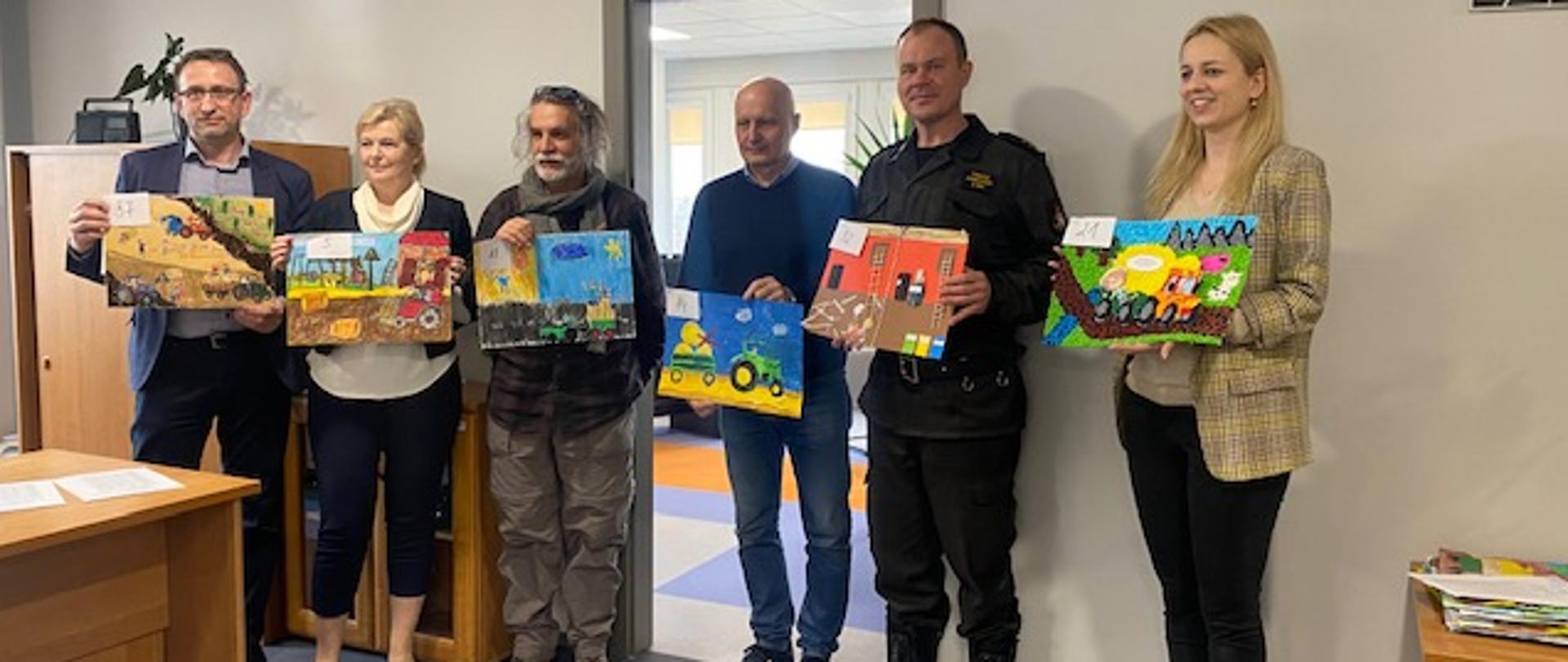 Pracownicy KRUS oraz funkcjonariusz PSP z pracami plastycznymi