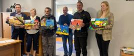 Pracownicy KRUS oraz funkcjonariusz PSP z pracami plastycznymi