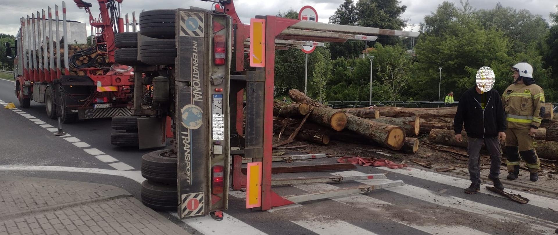 Na zdjęciu ciężarówkę z wywróconą z rozsypanym drewnem 