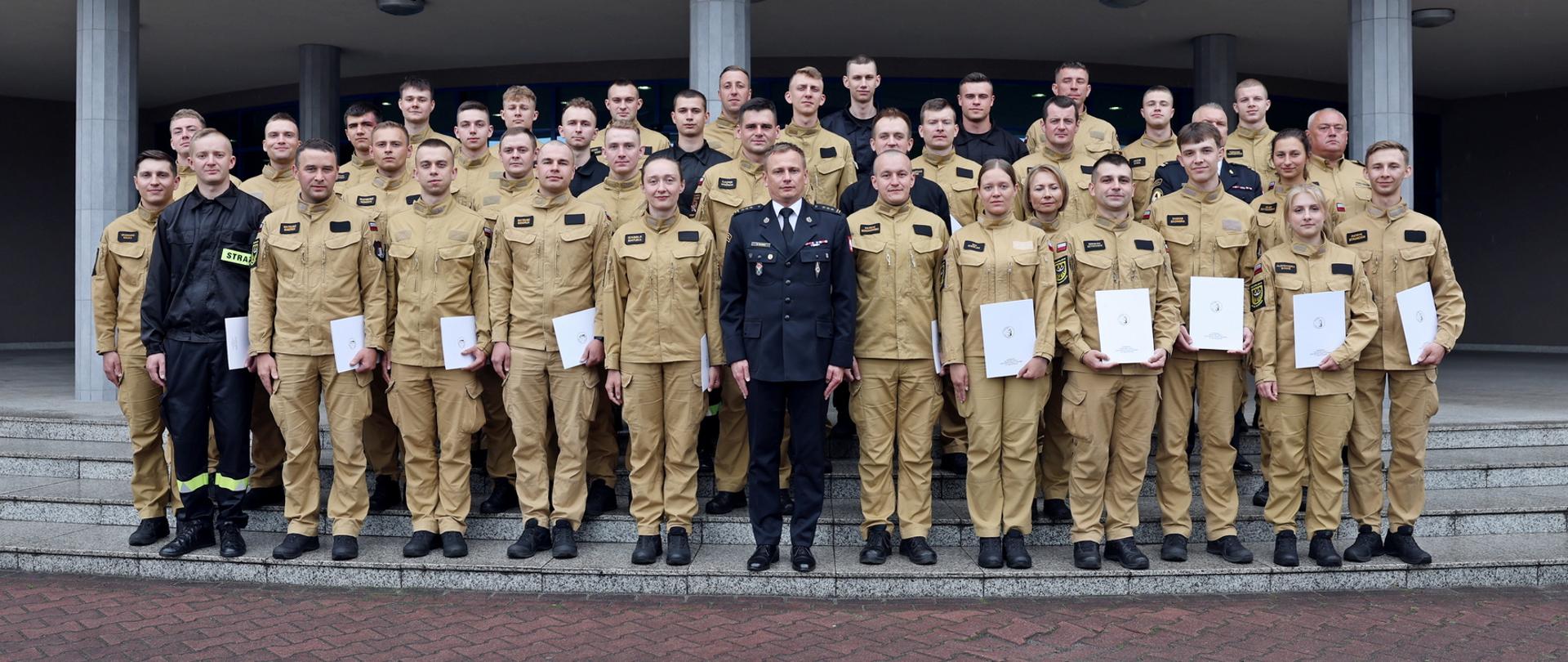 Pamiątkowe zdjęcie grupowe funkcjonariuszy PSP kończących szkolenie p[odstawowe w zawodzie strażak (36 osób) w towarzystwie Zastępcy Komendanta Centralnej Szkoły PSP, funkcjonariuszki CS PSP oraz dwóch funkcjonariuszy CS PSP