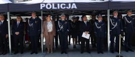 Wojewoda Opolski Monika Jurek oraz uczestnicy obchodów Święta Policji stoją pod namiotem z napisem "Policja".