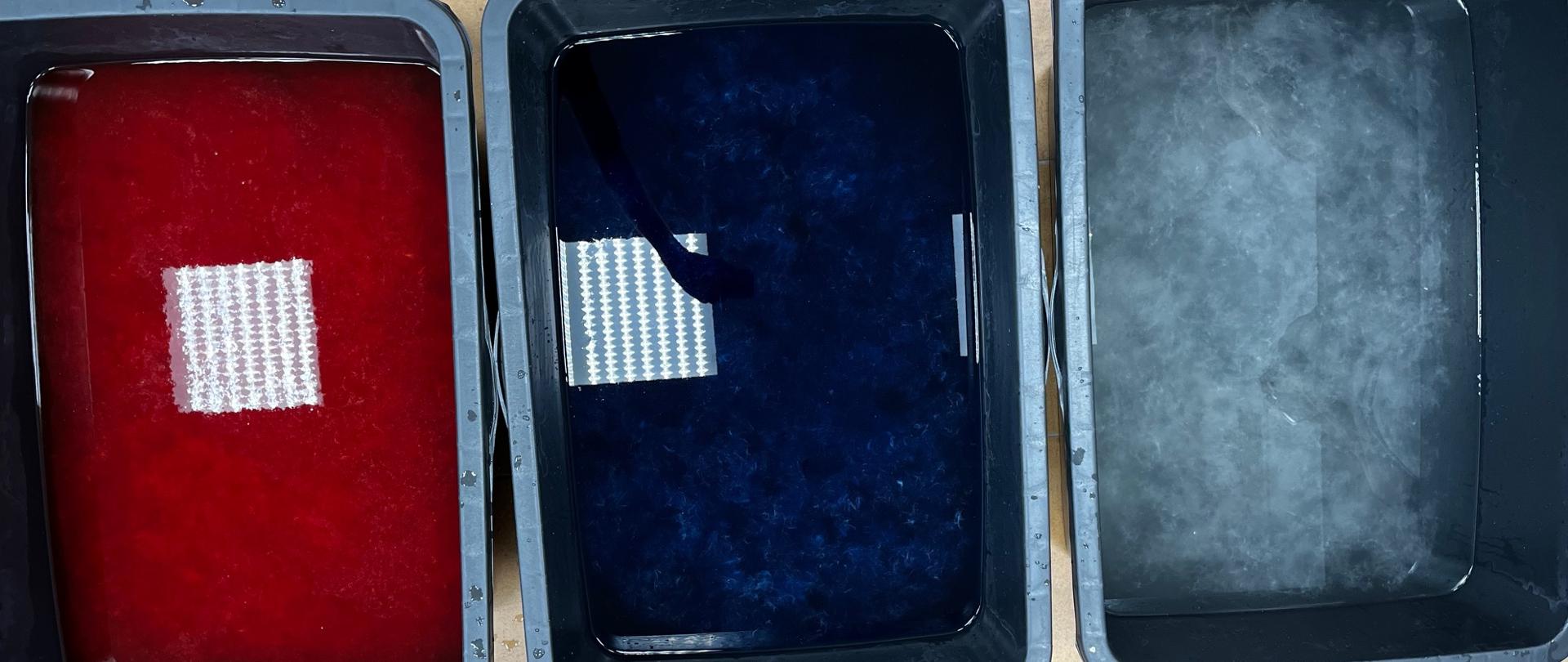 Trzy czarne plastikowe zbiorniki z barwnikami i wkłóknami