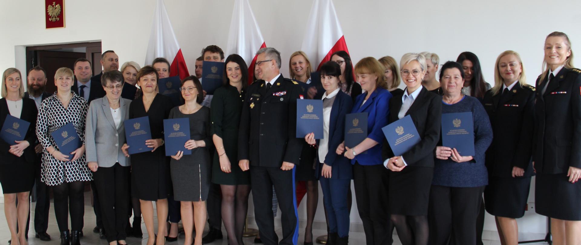 Zdjęcie grupowe - komendant wojewódzki - generał PSP, w otoczeniu pracowników. W rękach trzymane są listy gratulacyjne.