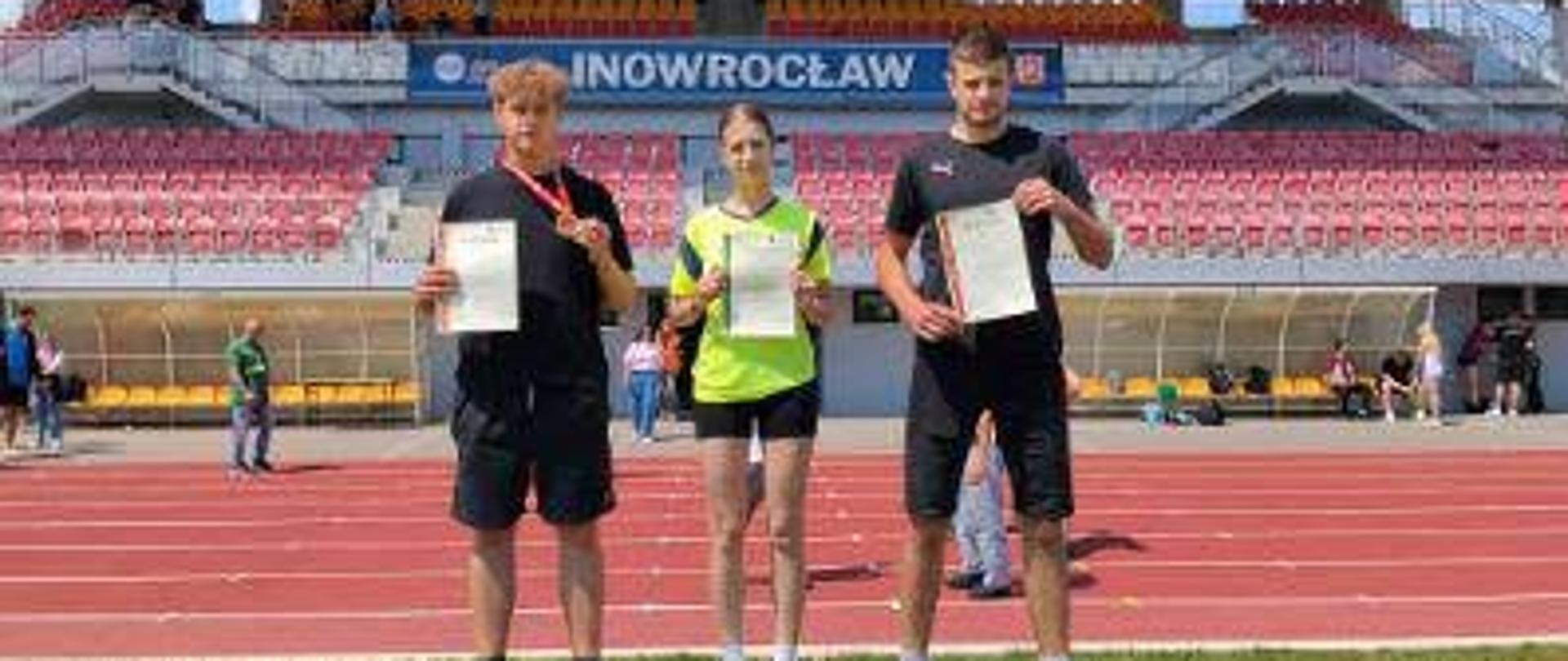widok stadionu -- Mistrzostwa LA woj. kuj.-pom. w Inowrocławiu, stoją na podium od lewej: Marek Pawełczak, Martyna Ciepłuch, Janek Podsiadło