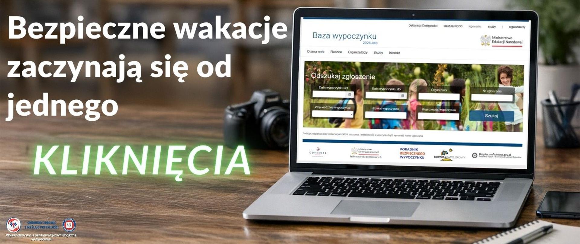 Komputer stojący na drewnianym stole z wyświetloną stronę internetową "Bazy wypoczynku" Ministerstwa Edukacji Narodowej