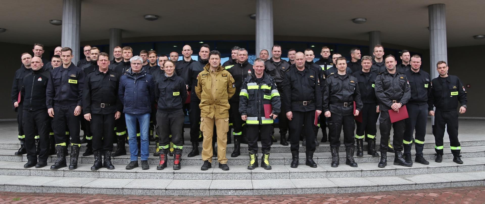 Grupowe zdjęcie uczestników warsztatów w towarzystwie Komendanta Centralnej Szkoły PSP, naczelnika wydziału nauczania oraz instruktorów