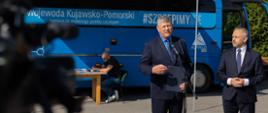 Na zdjęciu obecny wicewojewoda Józef Ramlau z samorządowcem. W tle niebieski autobus z napisem "Szczepimy się"