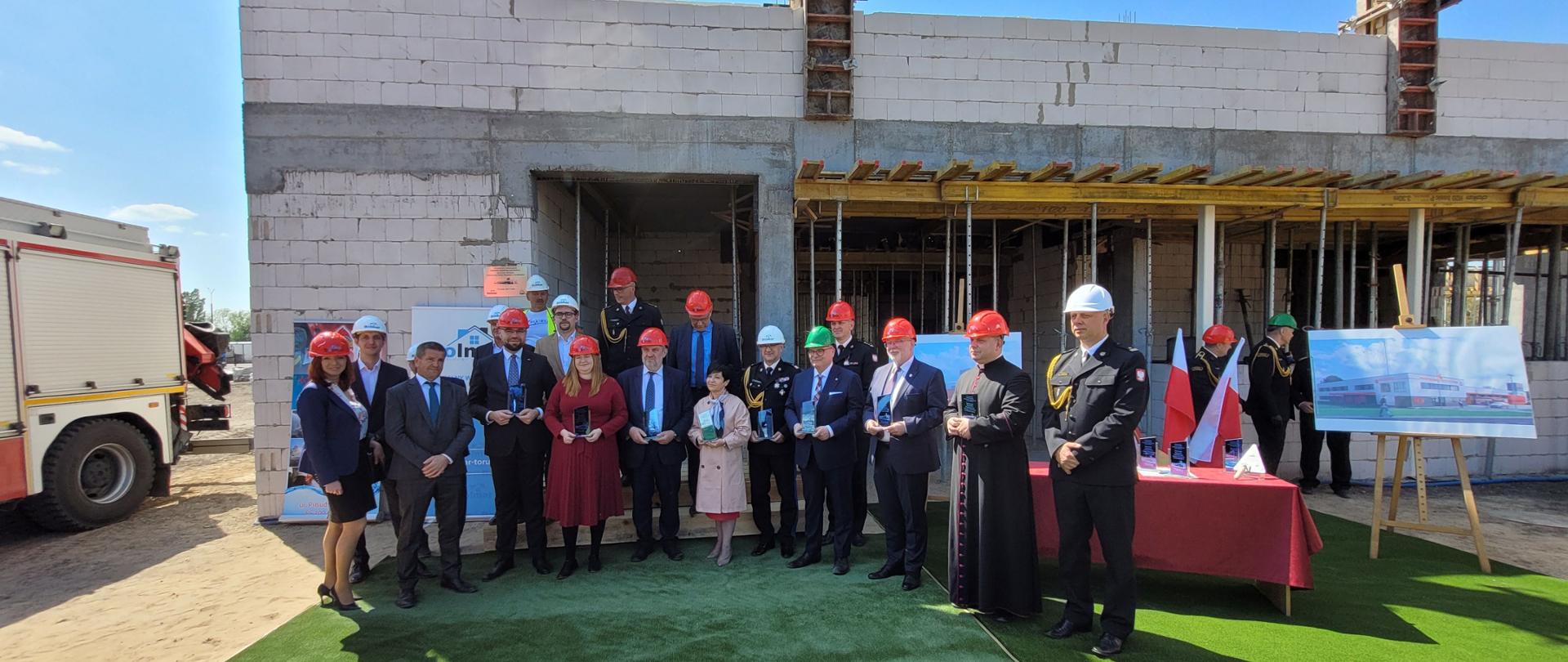 Pamiątkowe zdjęcie uczestników wydarzenia na tle budowanego obiektu.