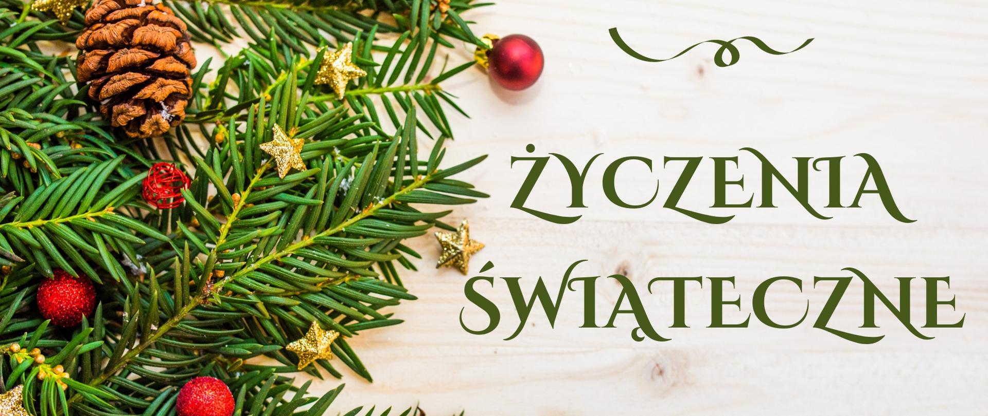 Grafika z teksturą jasnego drewna. Po lewej zielone gałązki świerka z czerwonymi i złotymi ozdobami. Po prawej napis w kolorze zielonym Życzenia Świąteczne, nad nim motyw ozdobny wstążki w kolorze zielonym. 
