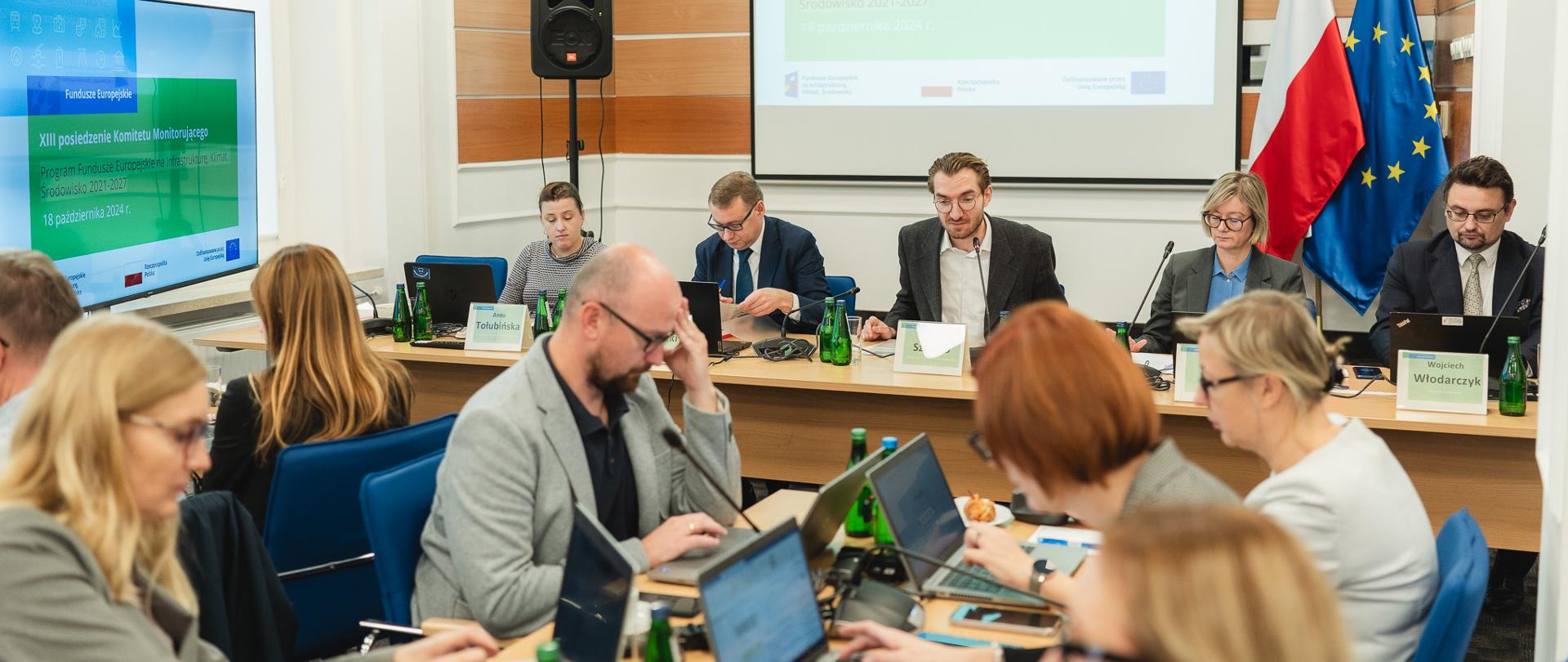 Widok sali konferencyjnej, gdzie przy stołach siedzą osoby. Wśród nich wiceminister Jan Szyszko.