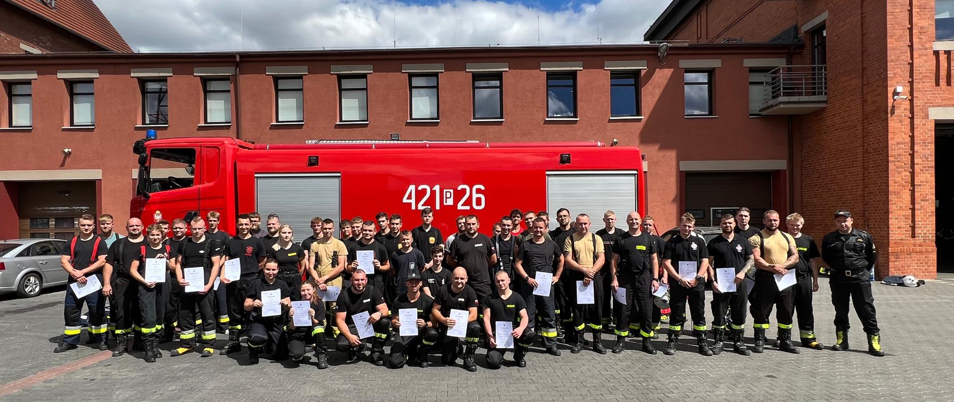 Zdjęcie zbiorowe kursantów zrobione na tle samochodu pożarniczego