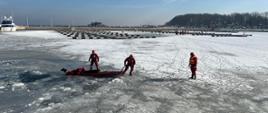 Ratownicy podejmują manekina z wody. W tle widać Marinę oraz molo w Pucku