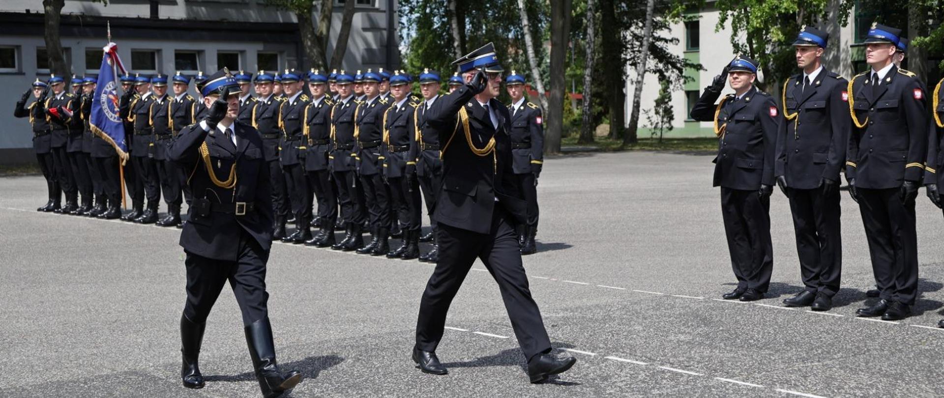 Z-ca komendanta głównego PSP wraz z dowódcą uroczystości maszeruje przed pododdziałem strazaków