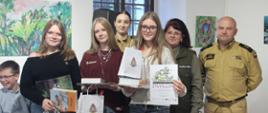Zdjęcie przedstawia laureatów konkursu z nagrodami i dyplomem wraz z jury konkursu: przedstawicielką Nadleśnictwa oraz funkcjonariuszami Państwowej Straży Pożarnej.