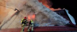 Zdjęcie przedstawia płonący budynek oraz strażaków
